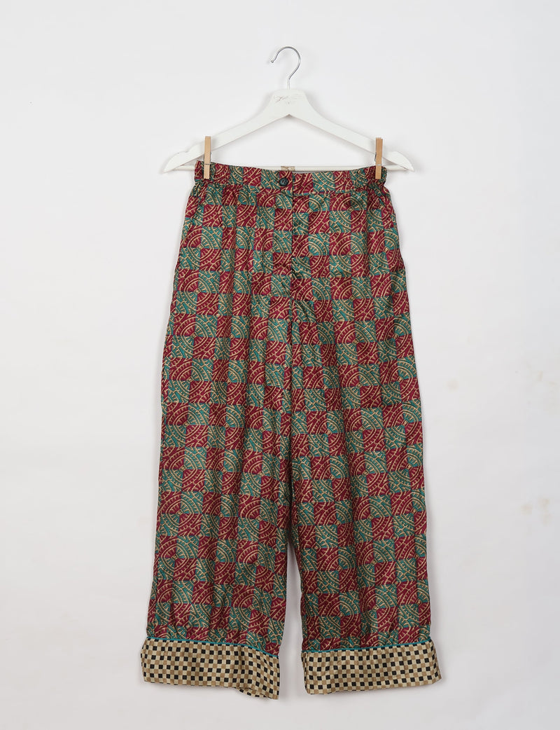 Red tropical patterned pajama pants with button and checkered cuffs, hanging on a white hanger