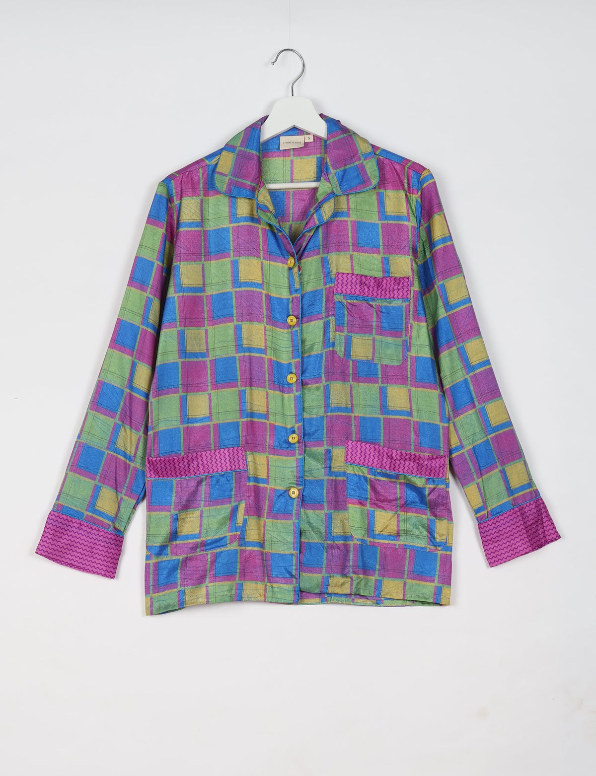 Long-sleeve pajama top in pink, green, blue, and yellow geometric pattern with button front and patch pockets hanging on white hanger