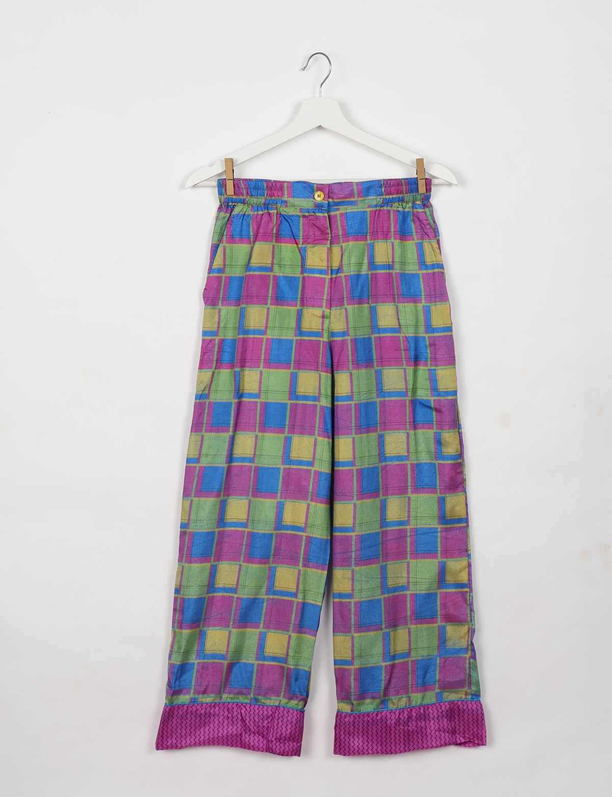 Pink geometric patterned pajama pants with elastic waistband and button, shown flat on hanger