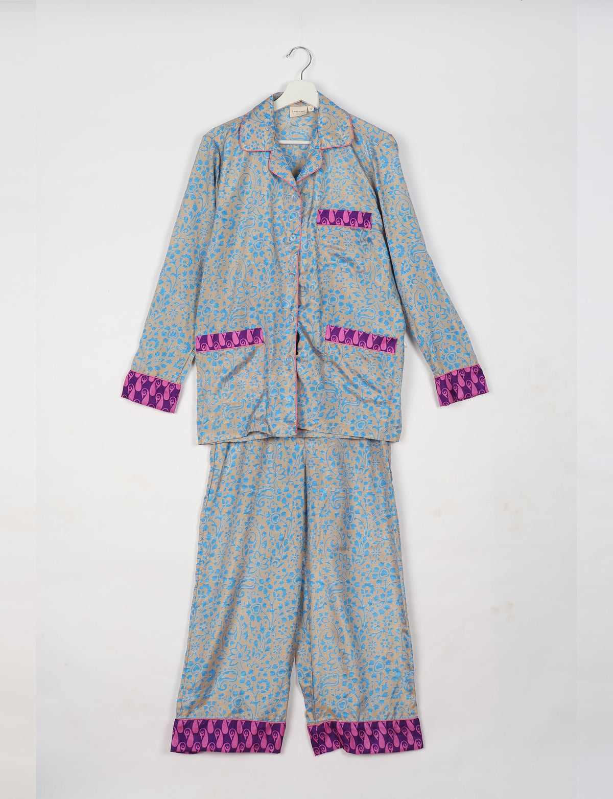 Blue and beige floral patterned long sleeve pajama set with purple and pink trim on cuffs, pockets, and pants hem, hanging flat