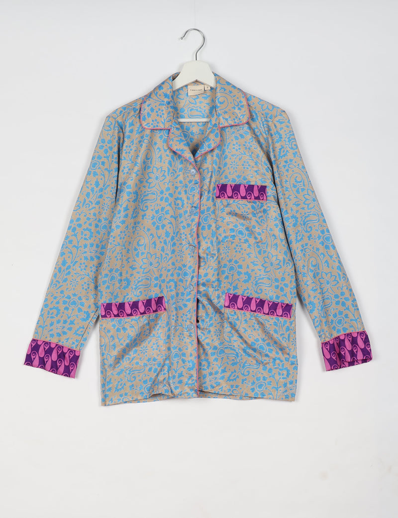 Long-sleeve blue floral patterned pajama top with purple and pink trim on cuffs and pockets, hanging on white hanger