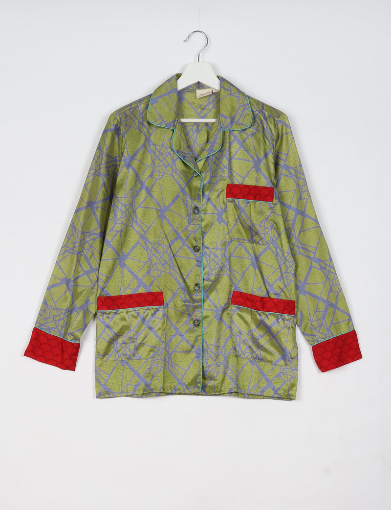 Long-sleeve green pajama top with abstract blue geometric pattern, red pocket and cuff accents, hanging on white hanger