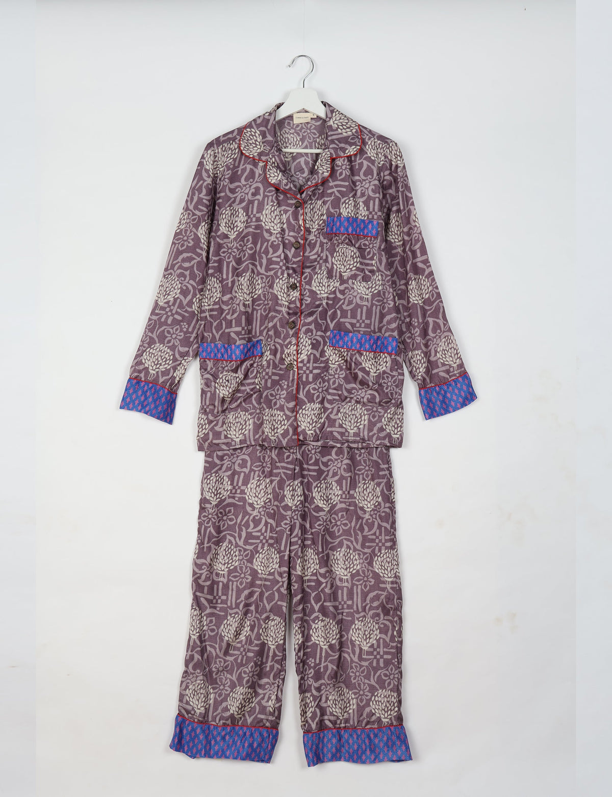 Purple floral long-sleeve pajama set with blue patterned cuffs and pocket trim, button front, hanging on white hanger
