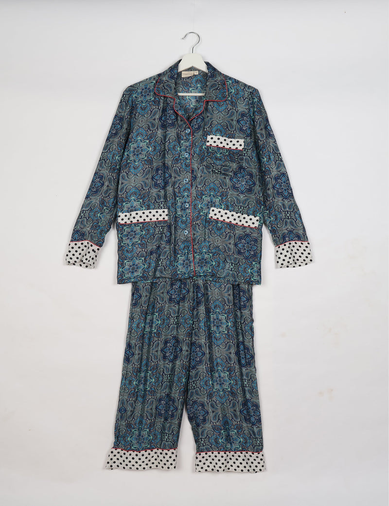 Long-sleeve pajama set with blue and grey floral paisley print, white polka dot cuffs and pockets, hanging on white hanger
