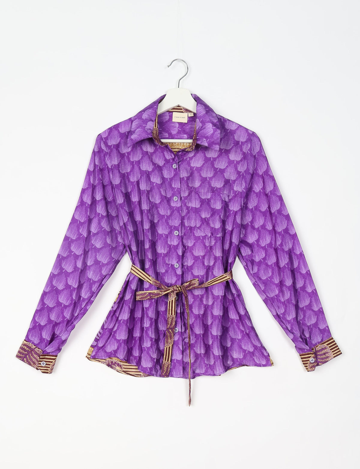 Purple button-up shirt with leaf pattern, long sleeves, collar, and patterned belt tied at waist, shown on hanger
