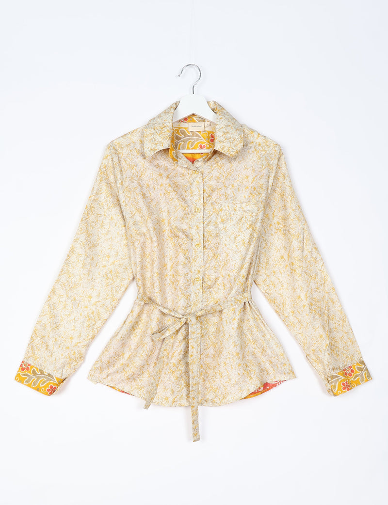 White long-sleeve button-up shirt with yellow abstract print, floral inner collar and cuffs, and waist tie, front view on hanger