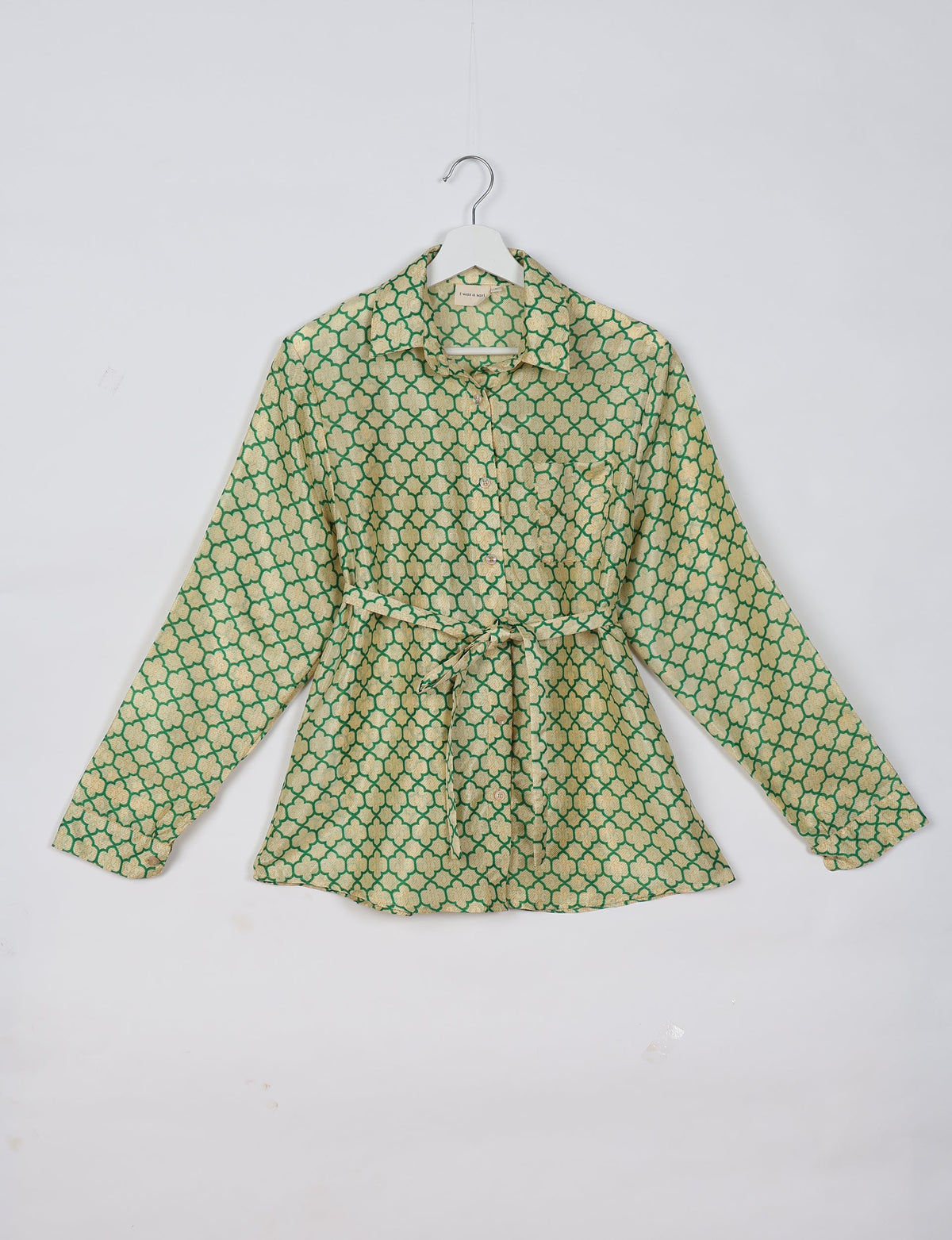 Long-sleeve shirt with green and beige geometric pattern, button front, collar, and waist tie, hanging on white hanger