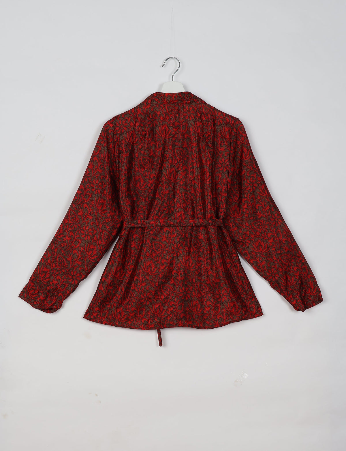 Red and black floral patterned long-sleeve shirt with a collar and adjustable waist belt, shown from the back on a hanger