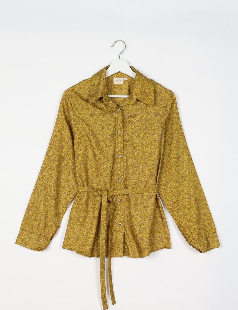 Yellow long-sleeve button-up shirt with brown tropical floral pattern and waist tie, hanging on white hanger front view