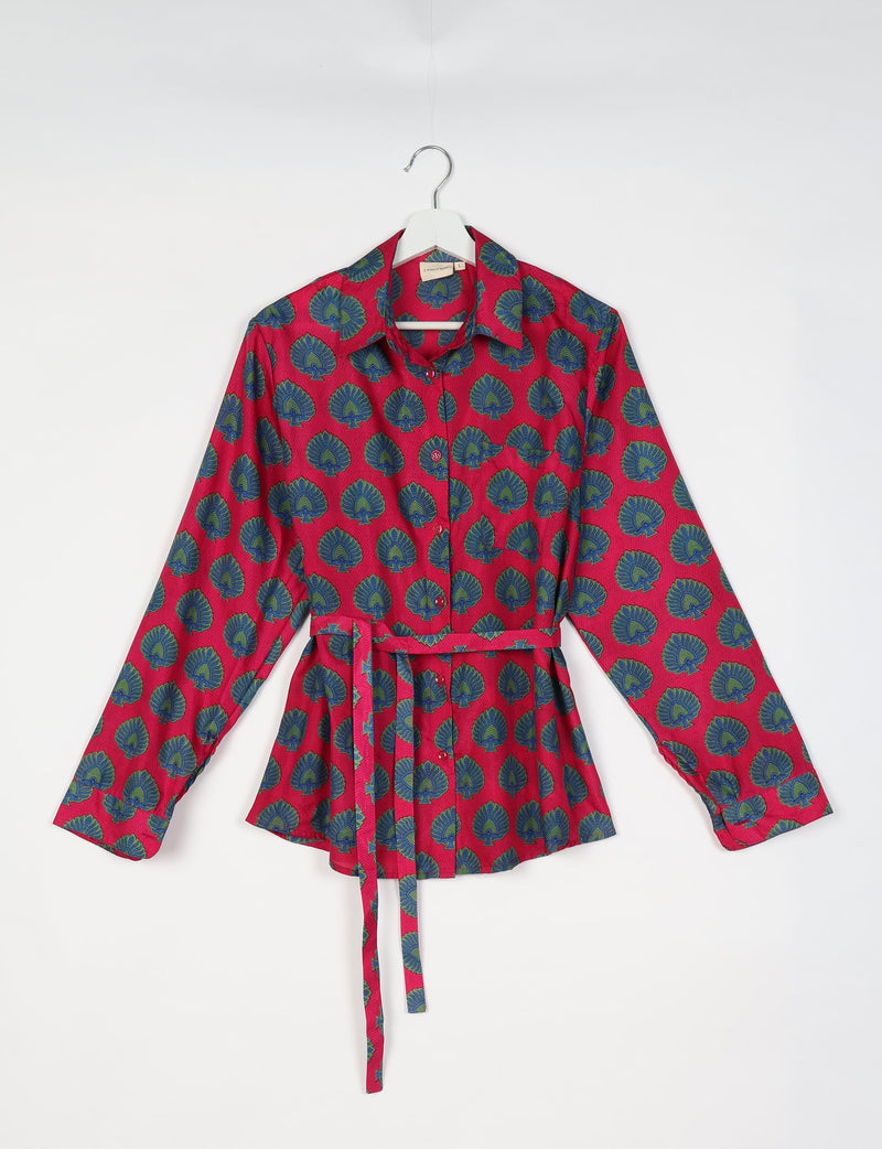 Red long-sleeve button-up shirt with blue and green leaf pattern, collar, and matching fabric belt, hanging on white hanger