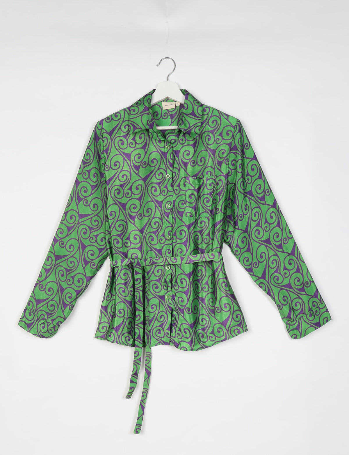 Green button-up shirt with purple abstract swirl pattern, long sleeves, chest pocket, and waist tie belt, front view on hanger