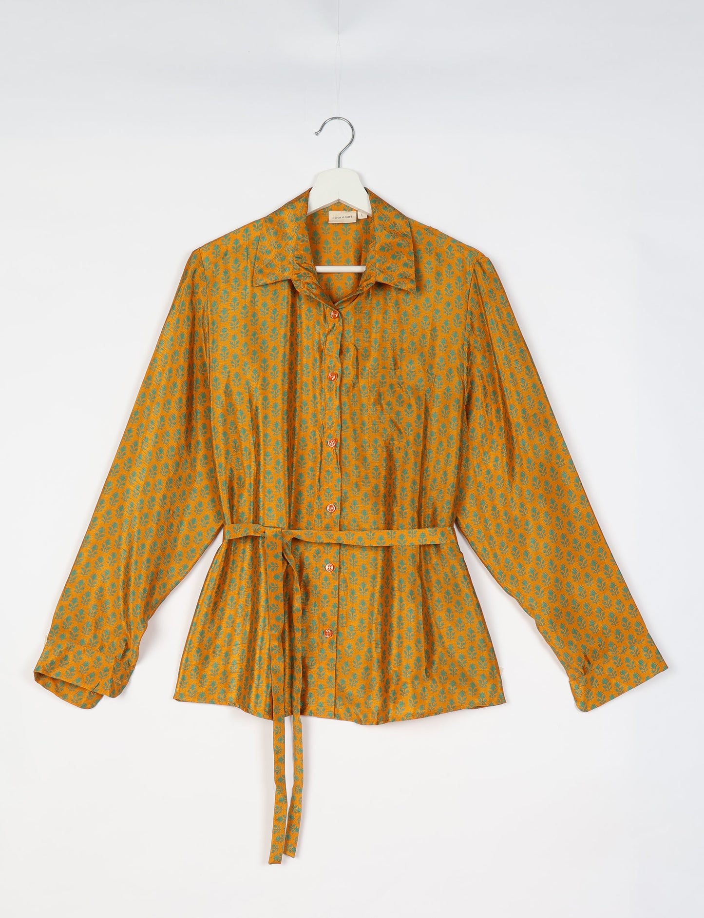 Experience sustainable fashion with our classic slim-fit shirt, crafted with ethical and green values. The shirt, designed for minimal waste, features a tie-up waist belt or neck tie, semi-spread collar, and regular shirt cuffs. Versatile and eco-friendly, wear it tucked in, unbuttoned over a tank top, or knotted at the waist for a unique style.