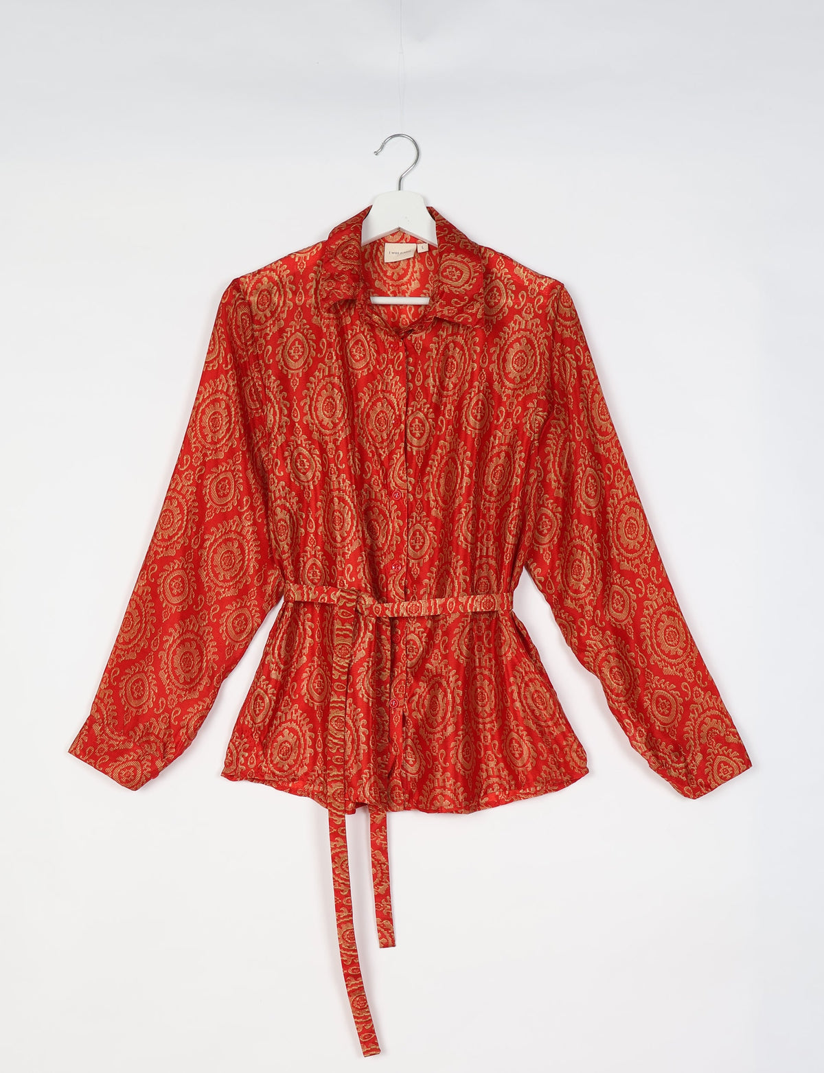 Orange shirt with Indian ethnic gold circular patterns, long sleeves, collar, buttons, and a matching fabric belt, hanging flat