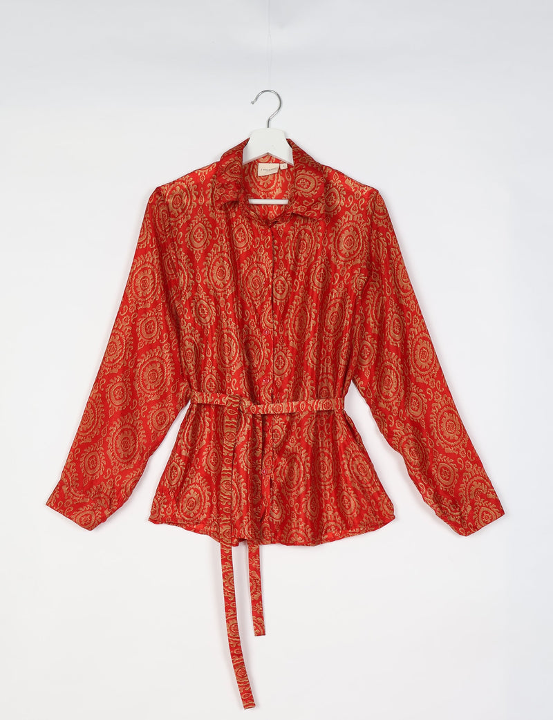 Orange shirt with Indian ethnic gold circular patterns, long sleeves, collar, buttons, and a matching fabric belt, hanging flat