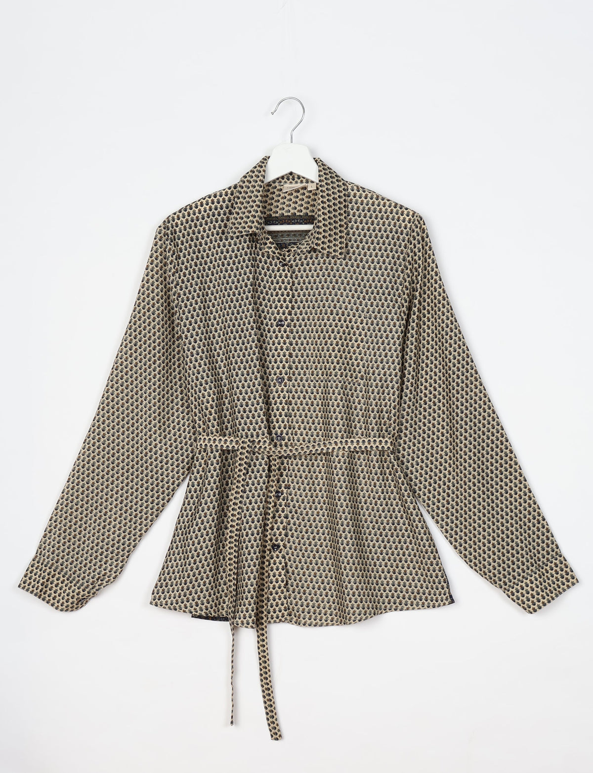 Beige long-sleeve button-up shirt with black micro floral pattern, collar, chest pocket, and waist tie, hanging on white hanger