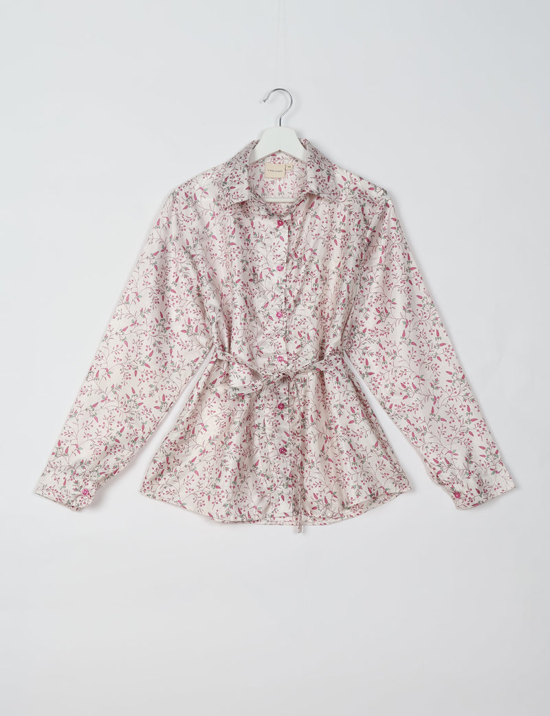 White button-up shirt with pink and green floral print, long sleeves, collar, and waist tie, hanging on white hanger