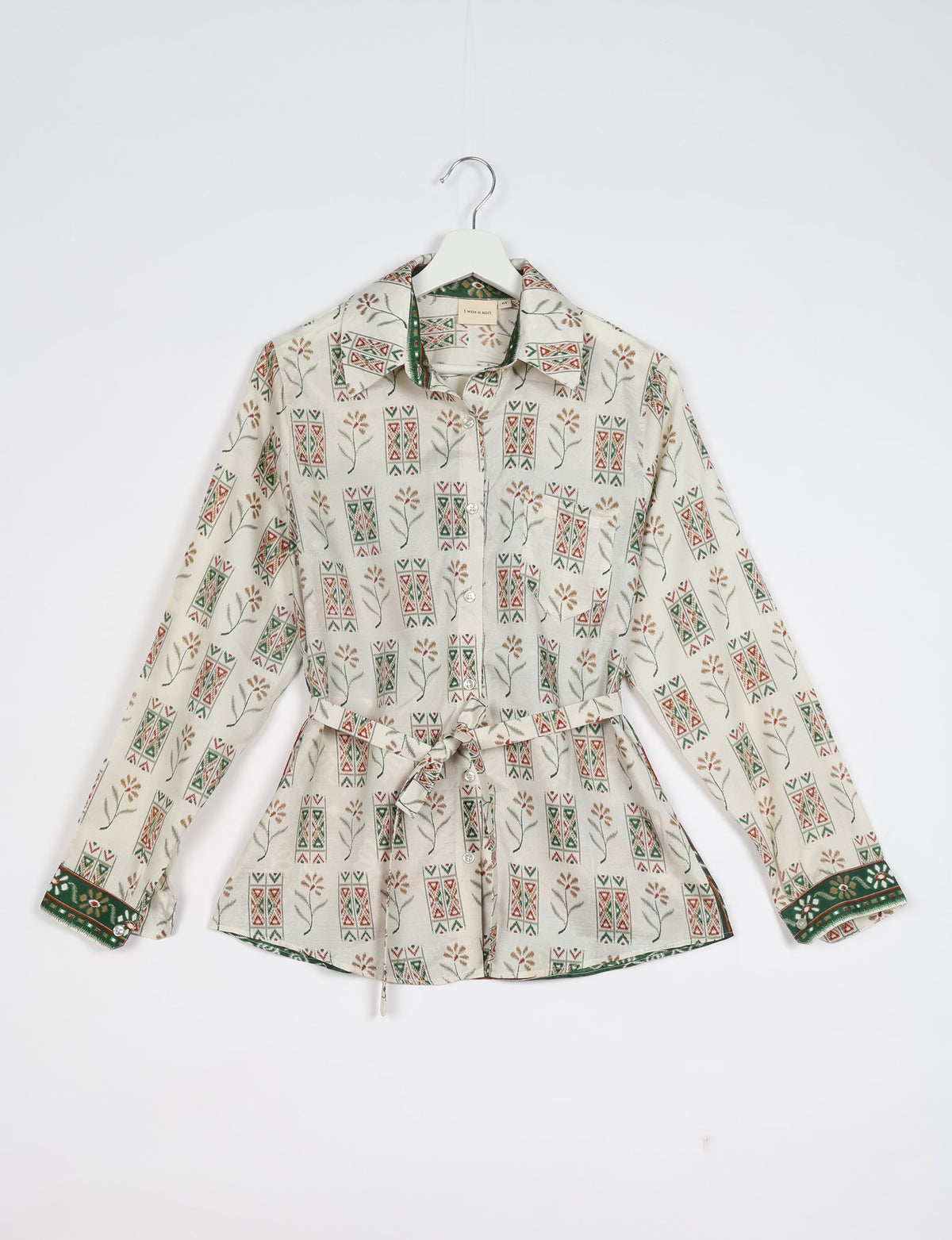 White Indian ethnic shirt with floral and geometric print, button front, long sleeves, and waist tie, shown on hanger