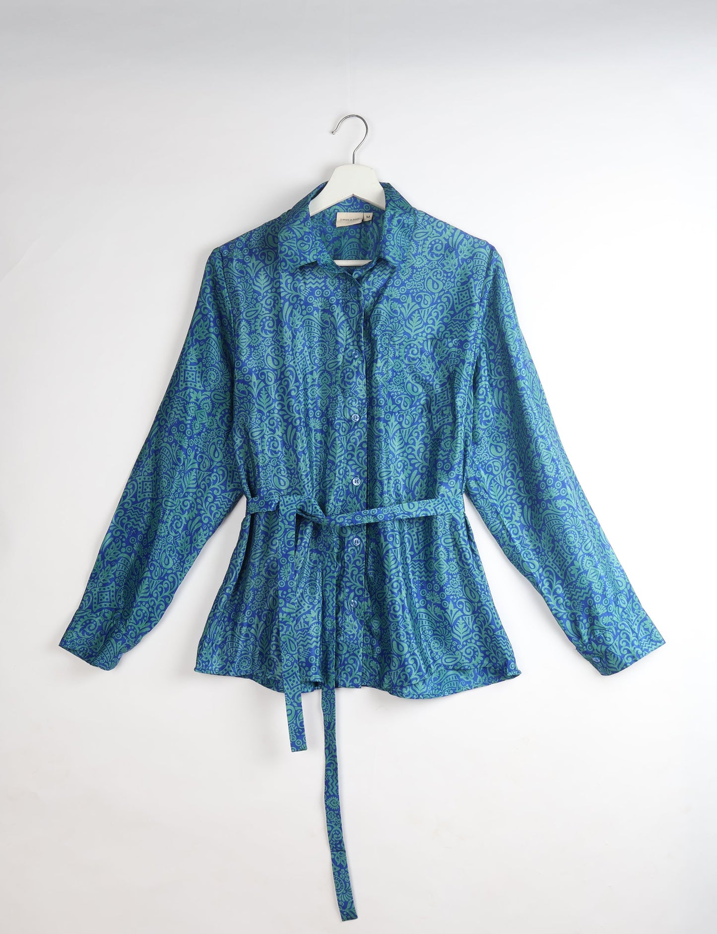 Experience sustainable fashion with our classic slim-fit shirt, crafted with ethical and green values. The shirt, designed for minimal waste, features a tie-up waist belt or neck tie, semi-spread collar, and regular shirt cuffs. Versatile and eco-friendly, wear it tucked in, unbuttoned over a tank top, or knotted at the waist for a unique style.