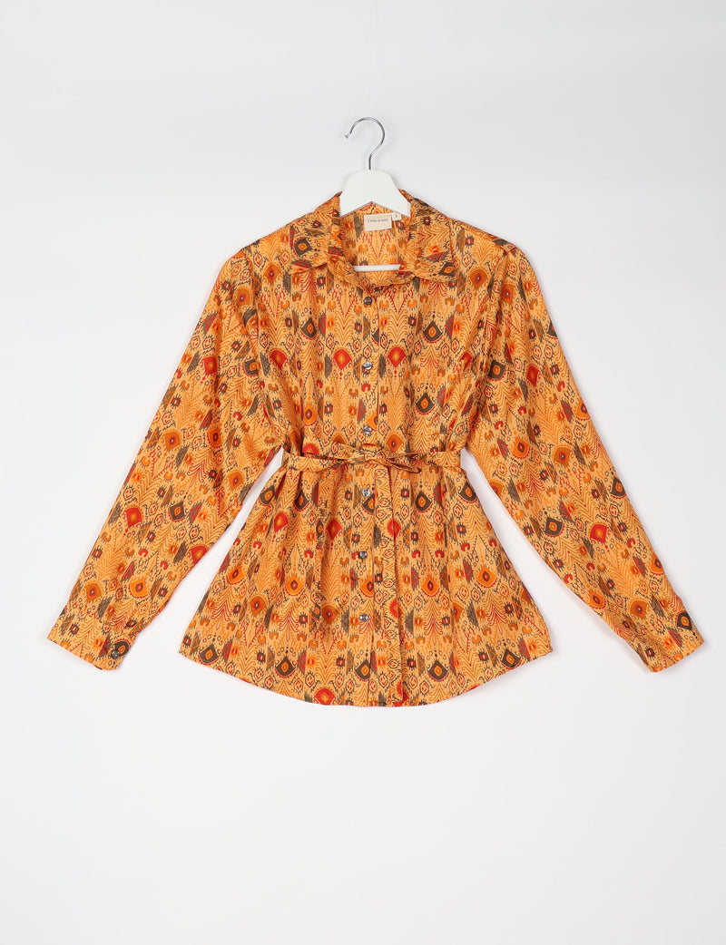 Orange ethnic patterned long-sleeve shirt with collar, button front, and matching fabric belt, shown flat on hanger