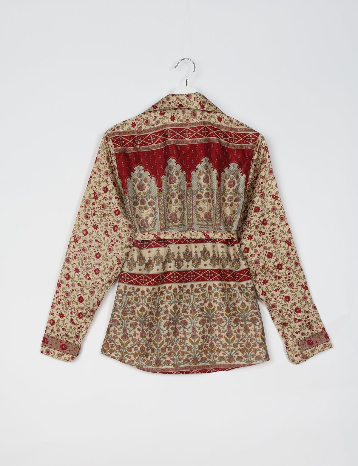 Beige long-sleeve shirt with red and multicolor floral and geometric tropical patterns, shown from back on hanger
