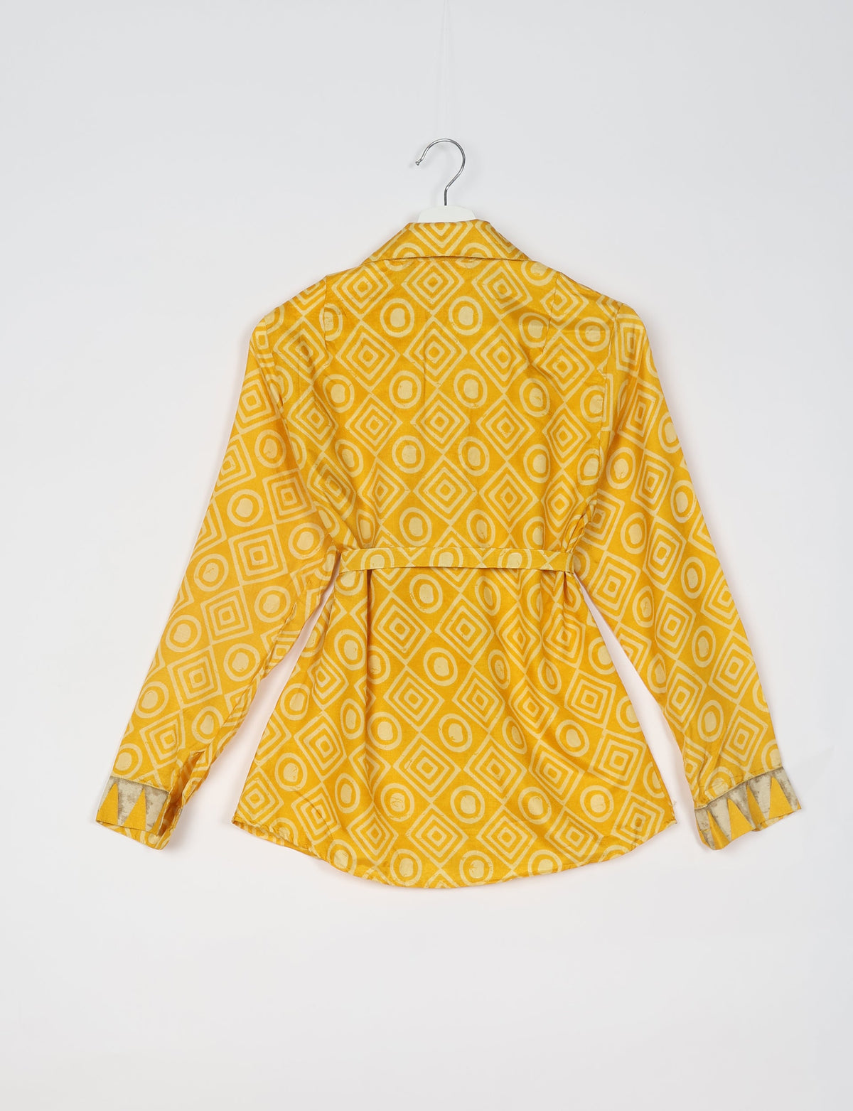 Yellow long-sleeve shirt with geometric diamond and circle pattern, back view, hanging on white hanger against white background