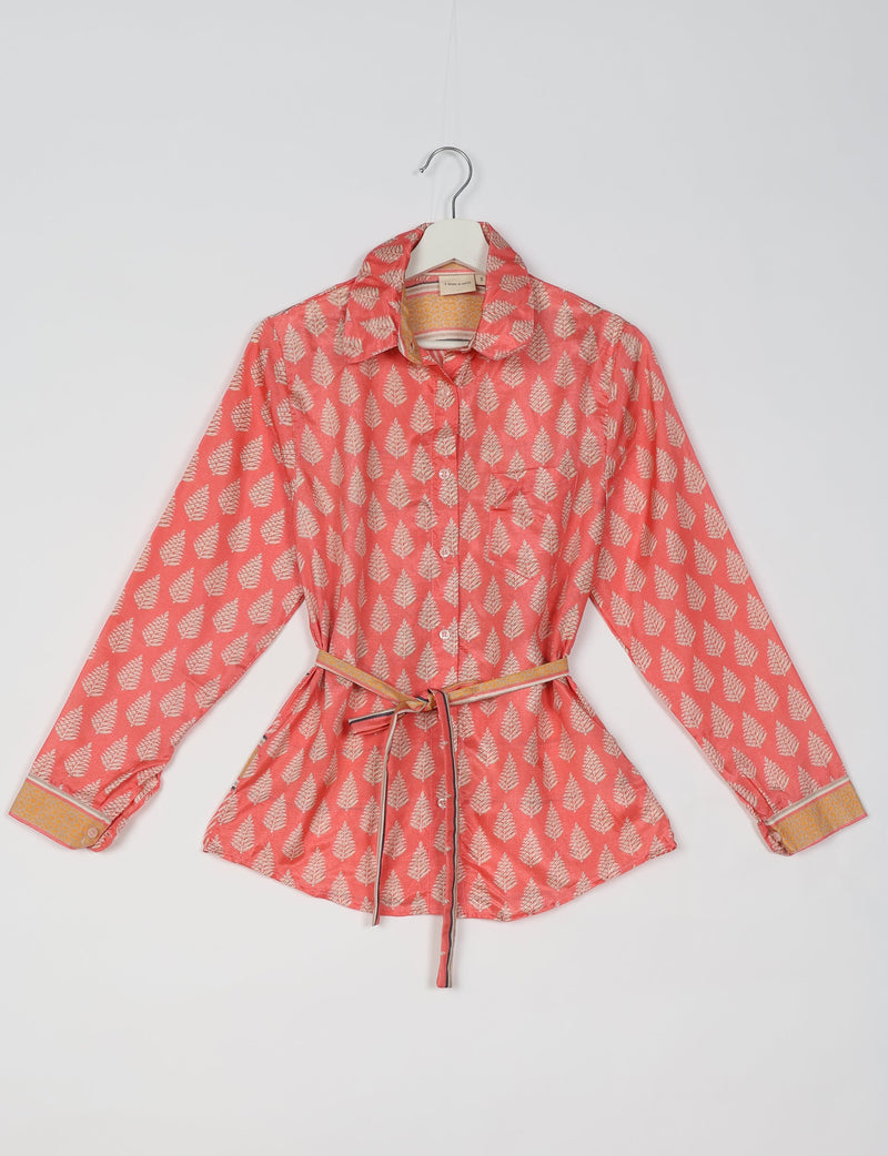 Coral pink ethnic shirt with white leaf print, long sleeves, button front, collar, and yellow patterned cuffs and belt, flat lay