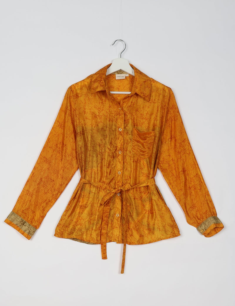 Orange long-sleeve button-up shirt with collar, chest pocket, tie waist, and contrasting cuff details hanging on white hanger