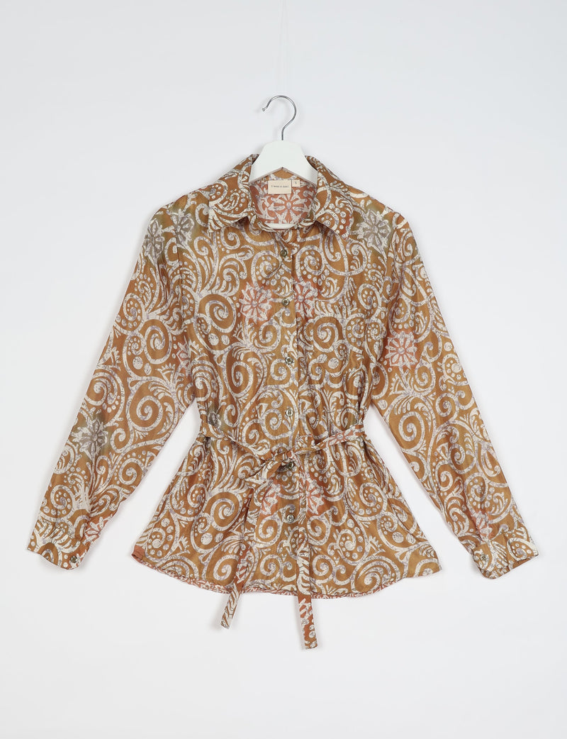 Brown long-sleeve button-up shirt with white and orange intricate swirl and floral ethnic patterns, hanging on white hanger