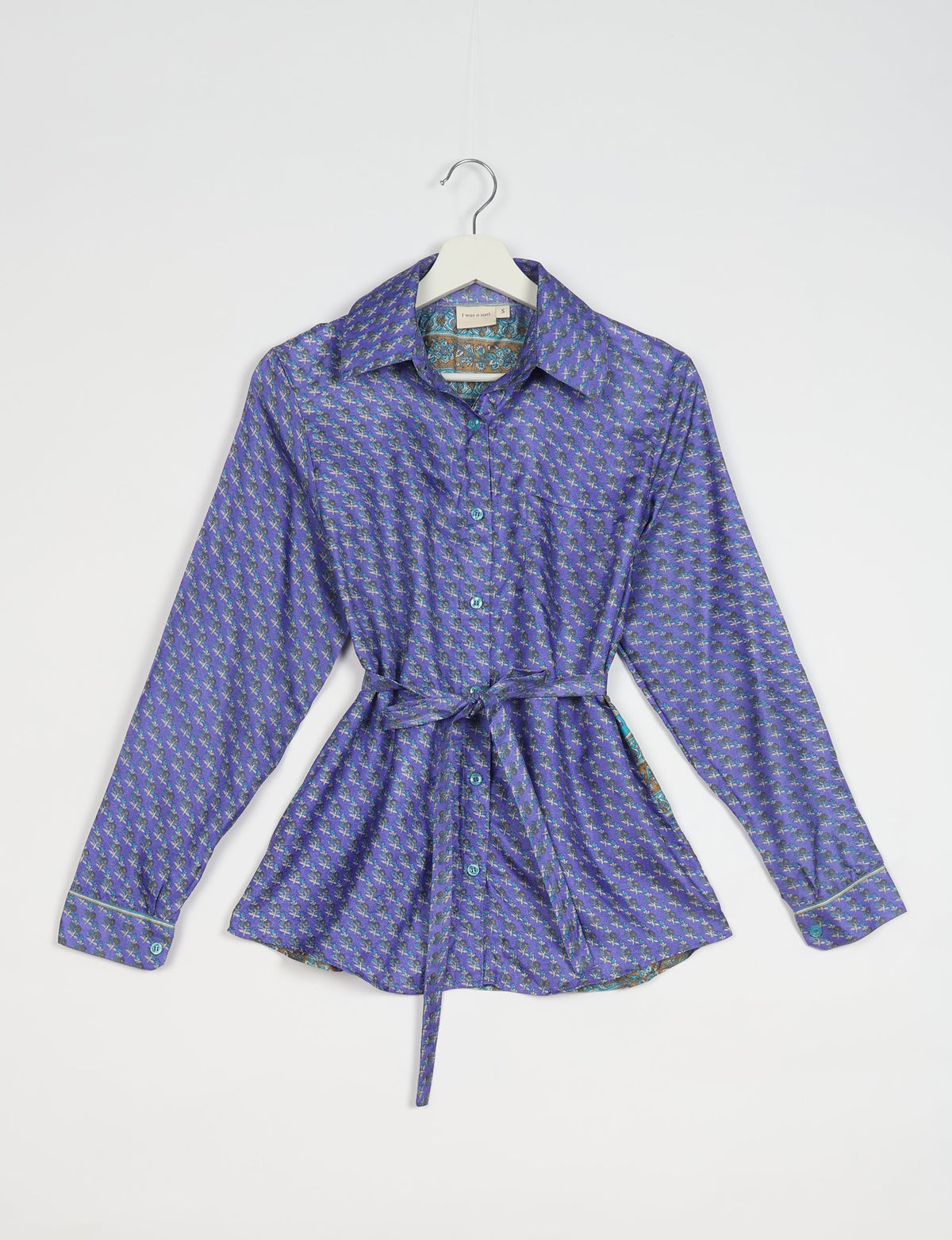 Blue Indian ethnic long-sleeve shirt with small floral pattern, button front, collar, and waist tie, hanging on white hanger
