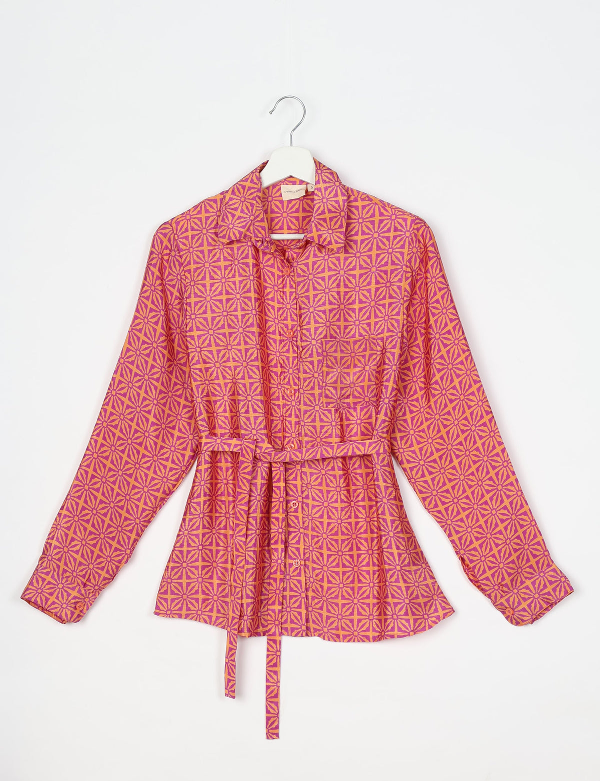 Pink and orange geometric patterned long-sleeve shirt with collar, button front, and waist tie, hanging on white hanger
