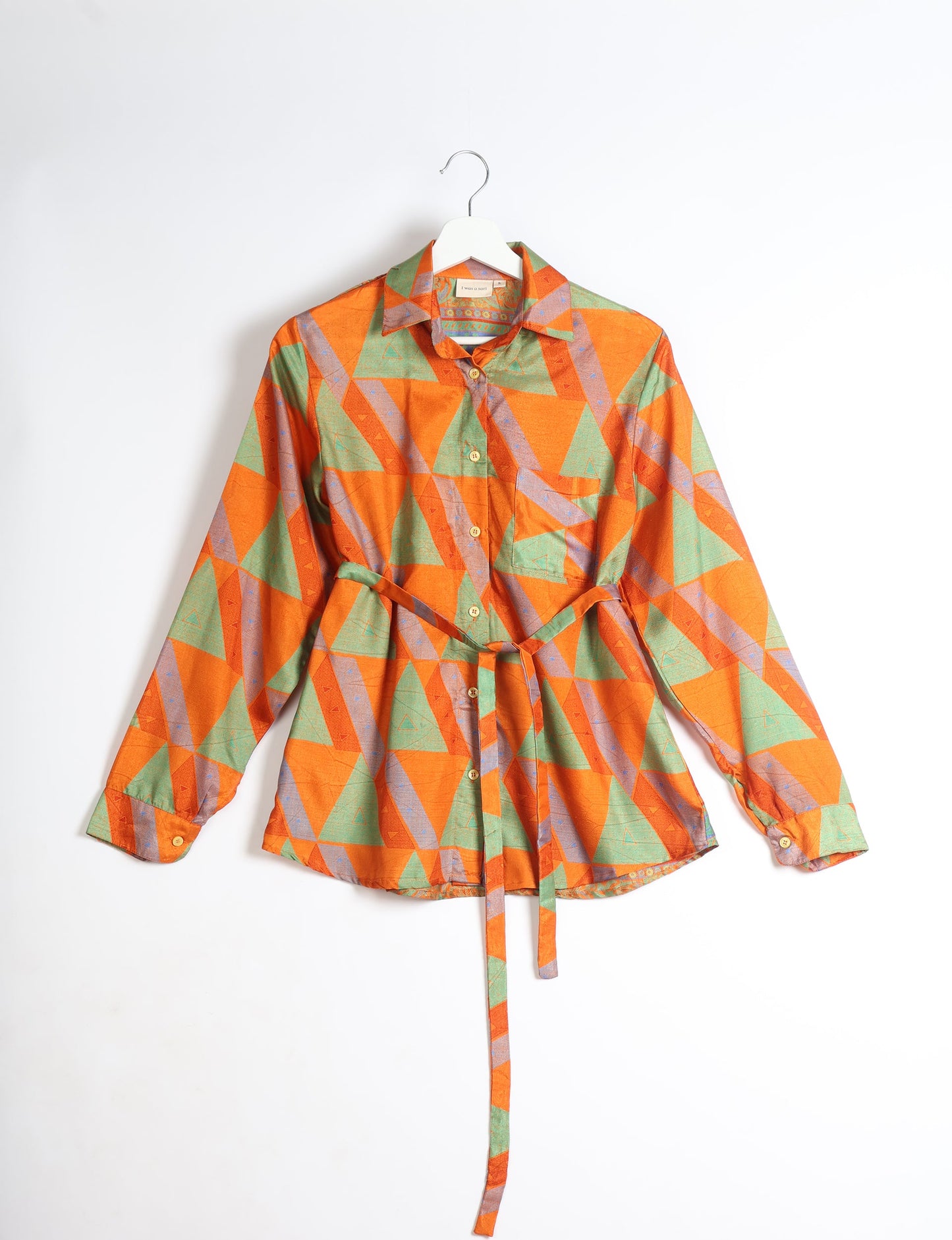 Experience sustainable fashion with our classic slim-fit shirt, crafted with ethical and green values. The shirt, designed for minimal waste, features a tie-up waist belt or neck tie, semi-spread collar, and regular shirt cuffs. Versatile and eco-friendly, wear it tucked in, unbuttoned over a tank top, or knotted at the waist for a unique style.