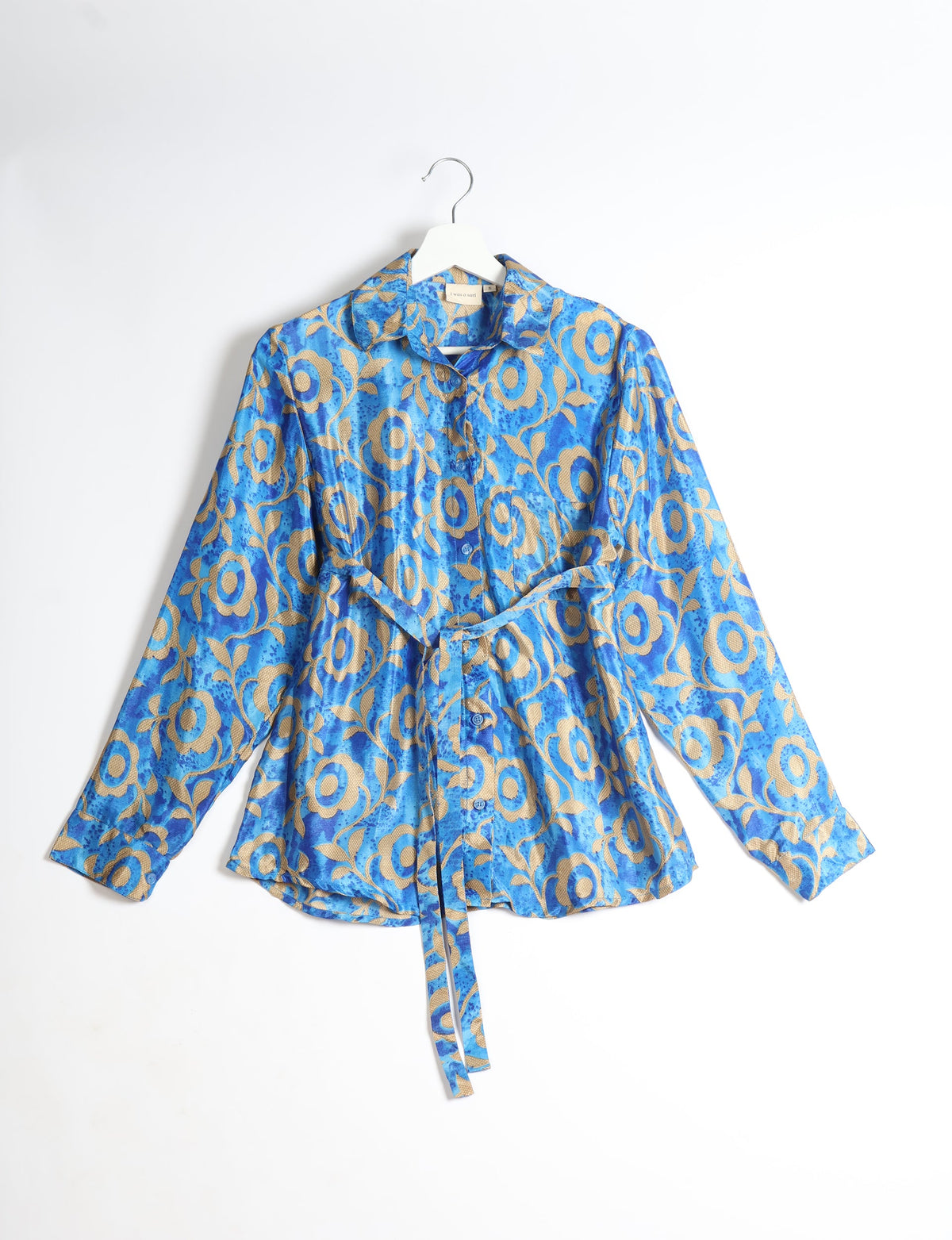Blue long-sleeve button-up shirt with beige floral pattern and matching fabric belt, hanging on white hanger front view