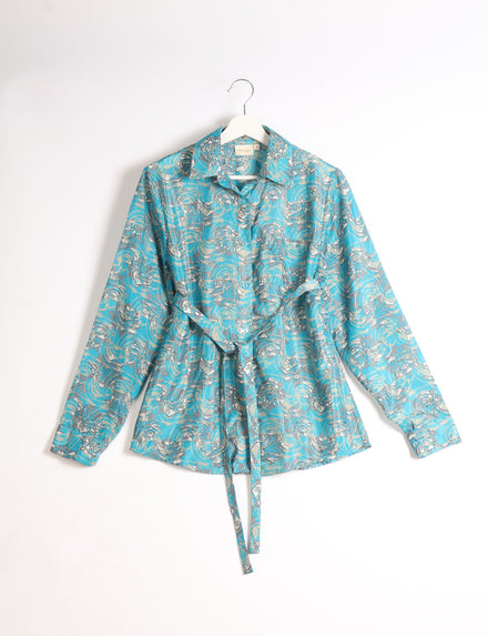 Blue long-sleeve button-up shirt with abstract white and gray floral pattern, collar, and waist tie, hanging on white hanger