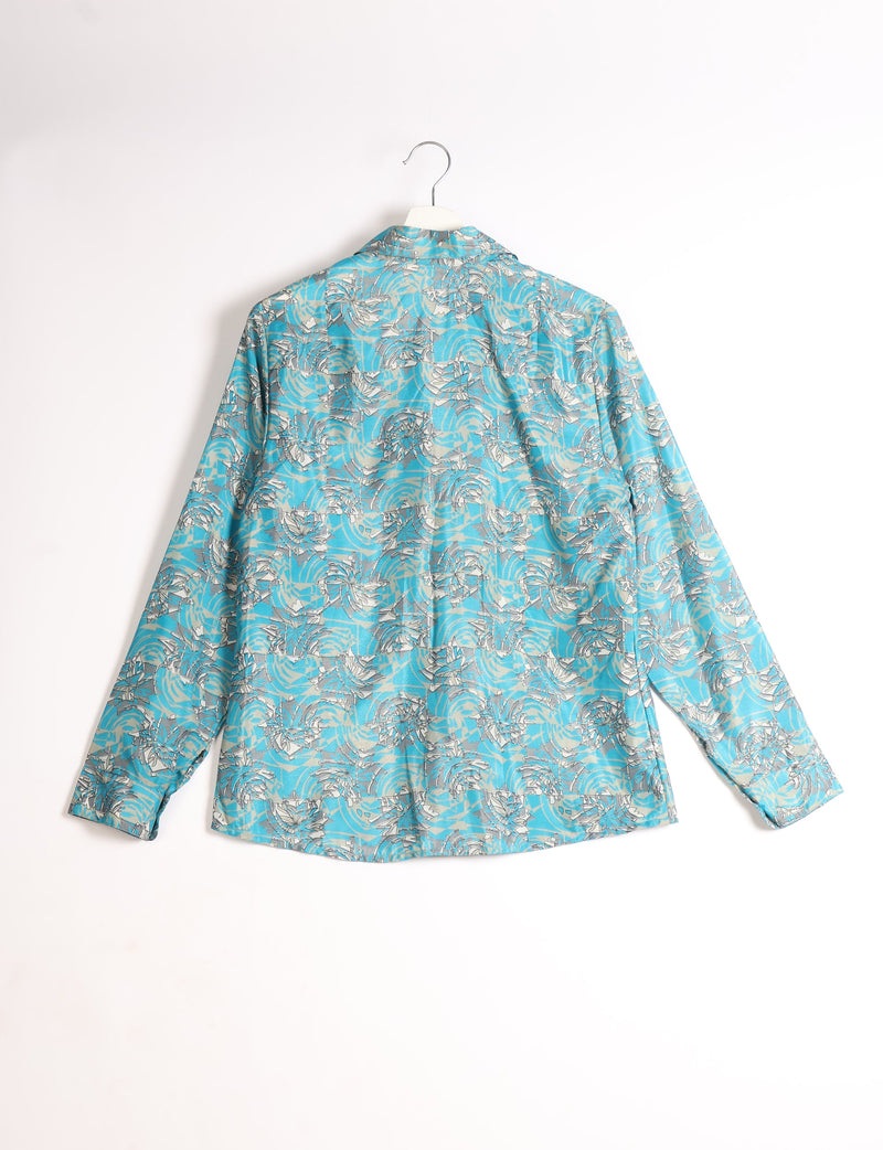 Blue long-sleeve shirt with abstract white and gray floral pattern, shown from back on white hanger against white background