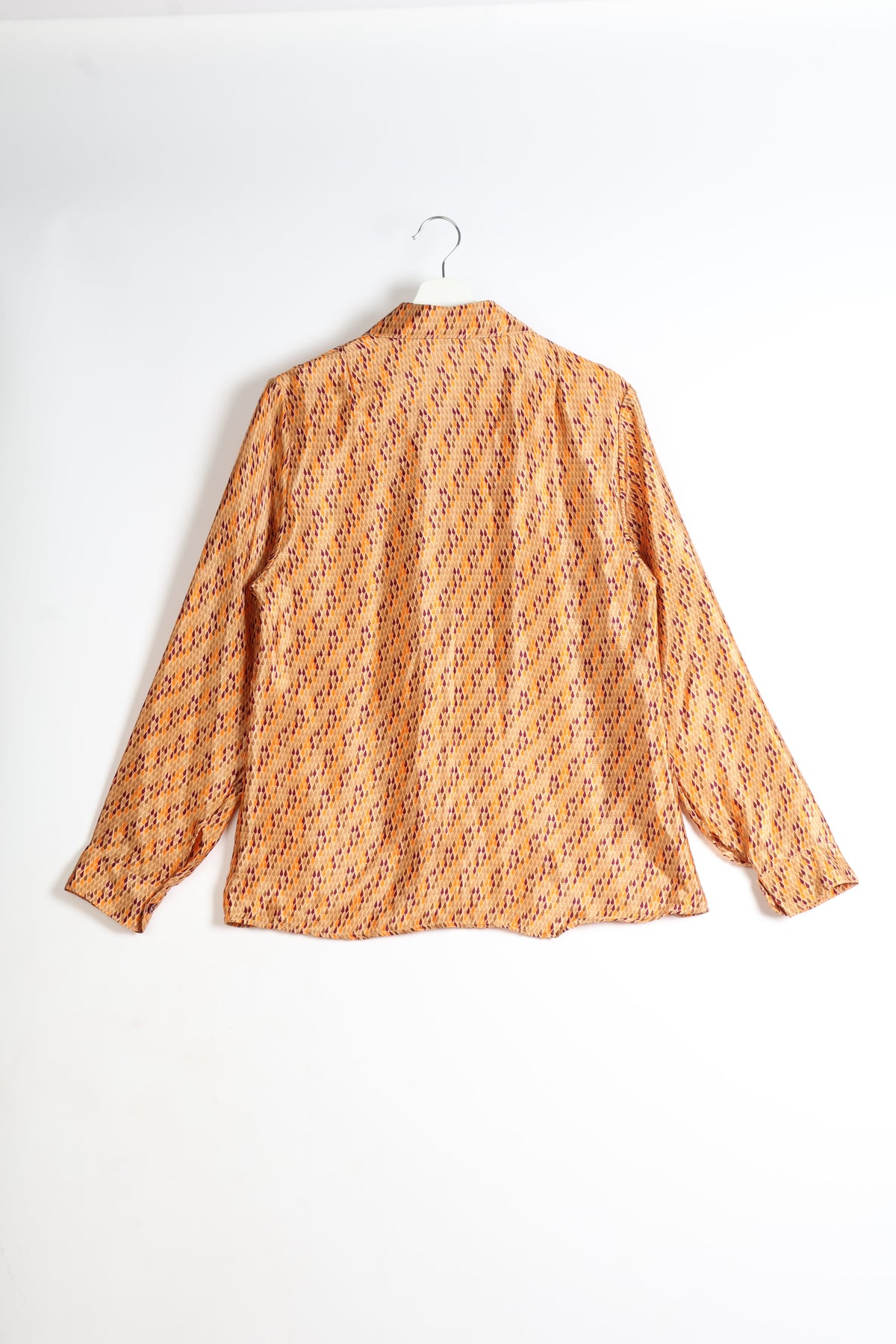 Orange long-sleeve shirt with micro diamond pattern in red and purple, shown from back on white hanger against white background