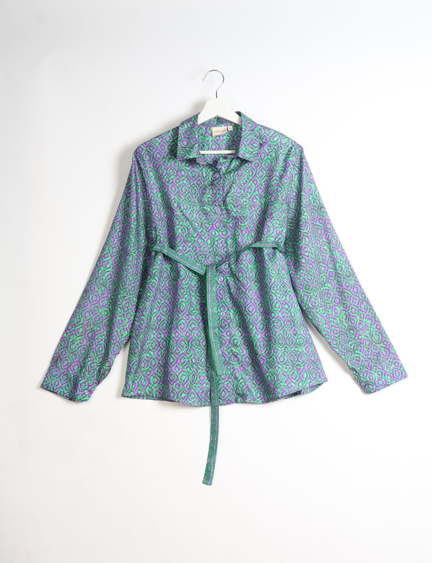 Experience sustainable fashion with our classic slim-fit shirt, crafted with ethical and green values. The shirt, designed for minimal waste, features a tie-up waist belt or neck tie, semi-spread collar, and regular shirt cuffs. Versatile and eco-friendly, wear it tucked in, unbuttoned over a tank top, or knotted at the waist for a unique style.