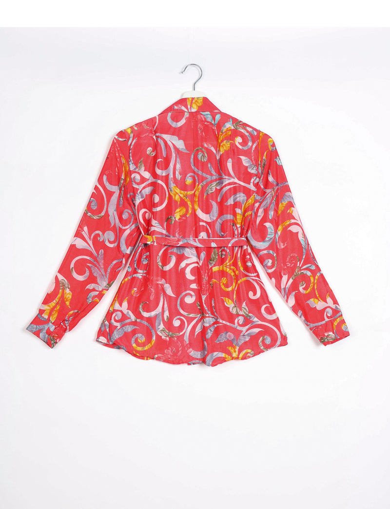 Long-sleeve orange shirt with abstract multicolor swirl pattern, buttoned cuffs, collar, and waist belt, back view on hanger