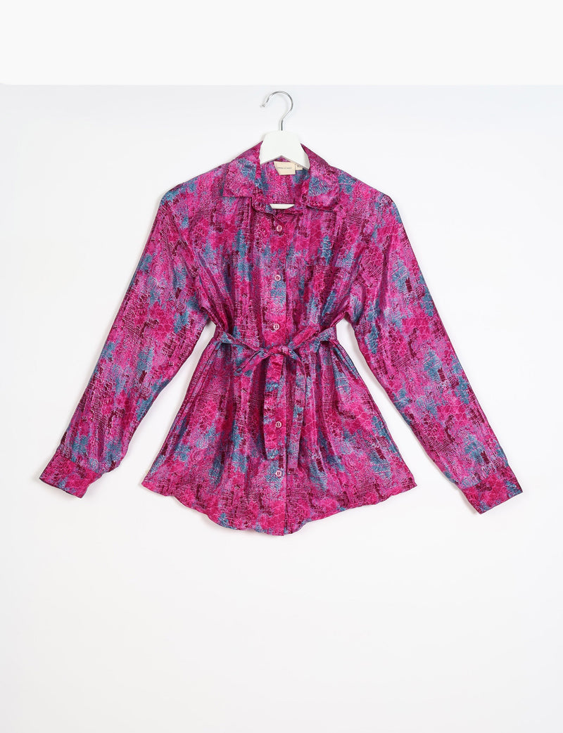 Pink and blue abstract patterned long-sleeve button-up shirt with collar and waist tie, hanging on white hanger, front view
