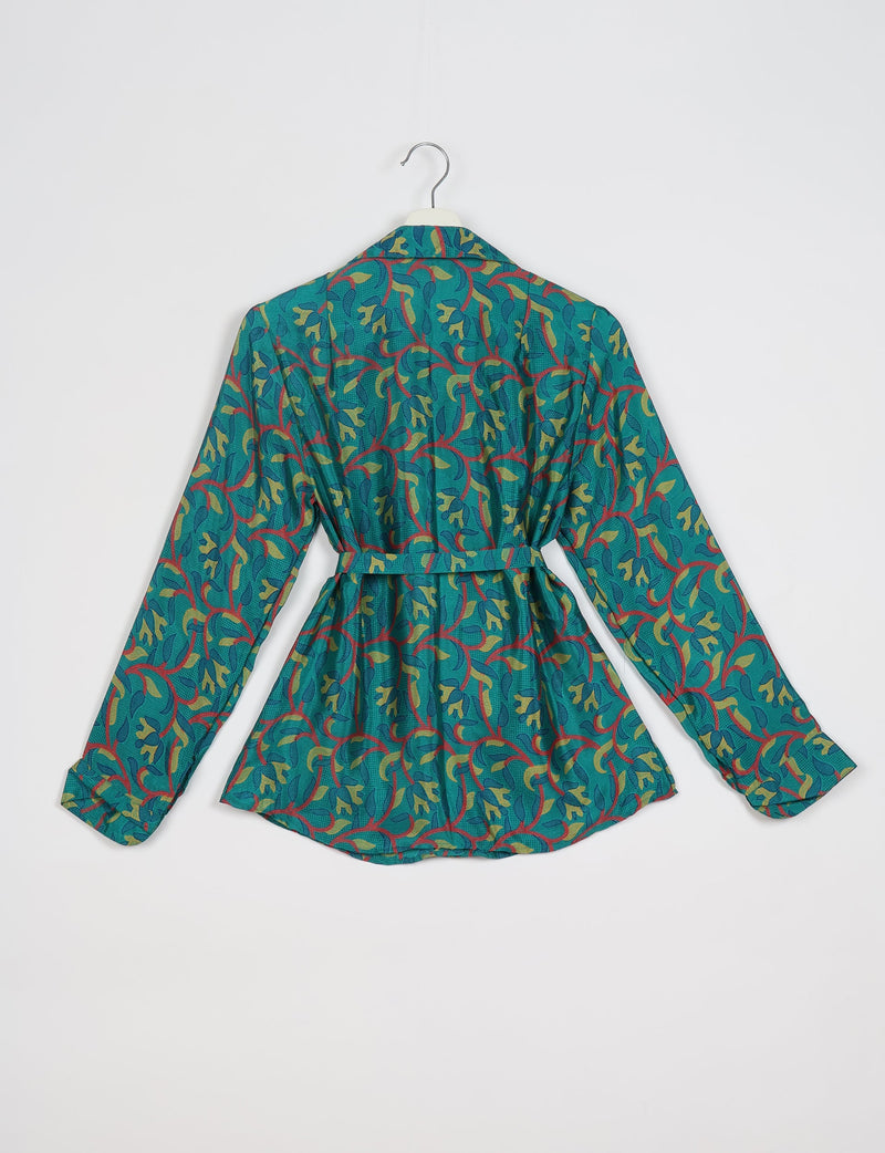 Blue long-sleeve shirt with abstract green, yellow, and red leaf pattern, belted waist, and collar, back view on hanger