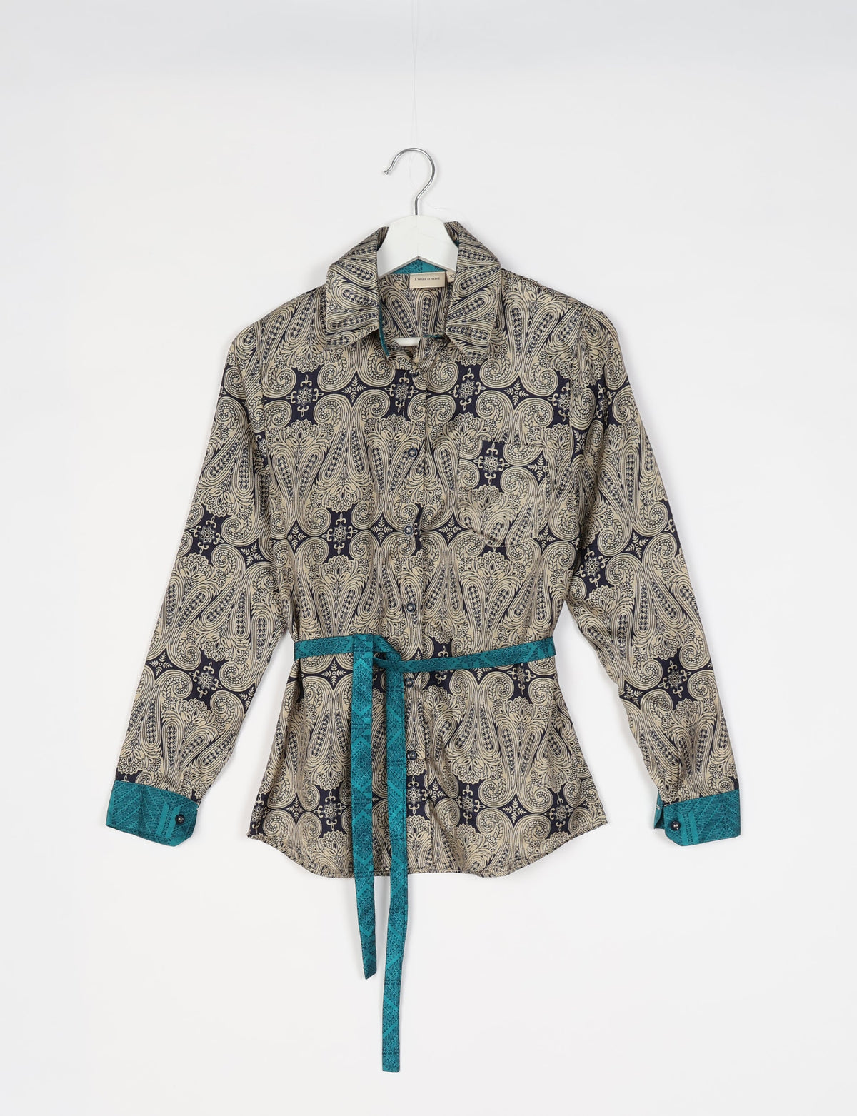 Long-sleeve grey paisley shirt with teal cuffs and belt, button front, hanging on white hanger, front view