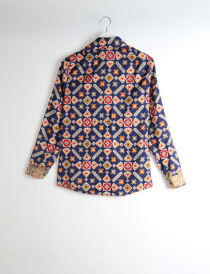 Long-sleeve shirt with navy blue base and geometric red, orange, beige, and white pattern, shown from back on hanger
