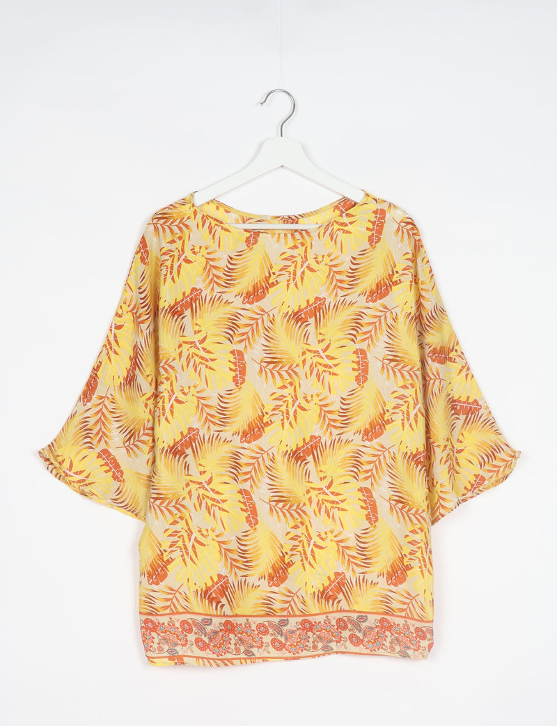 Yellow leaf-patterned belt top with wide sleeves and floral border hem, hanging on white hanger against white background