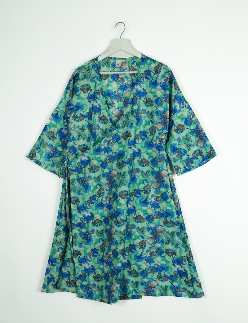 Green and blue abstract floral wrap coat with wide sleeves hanging on white hanger against white background