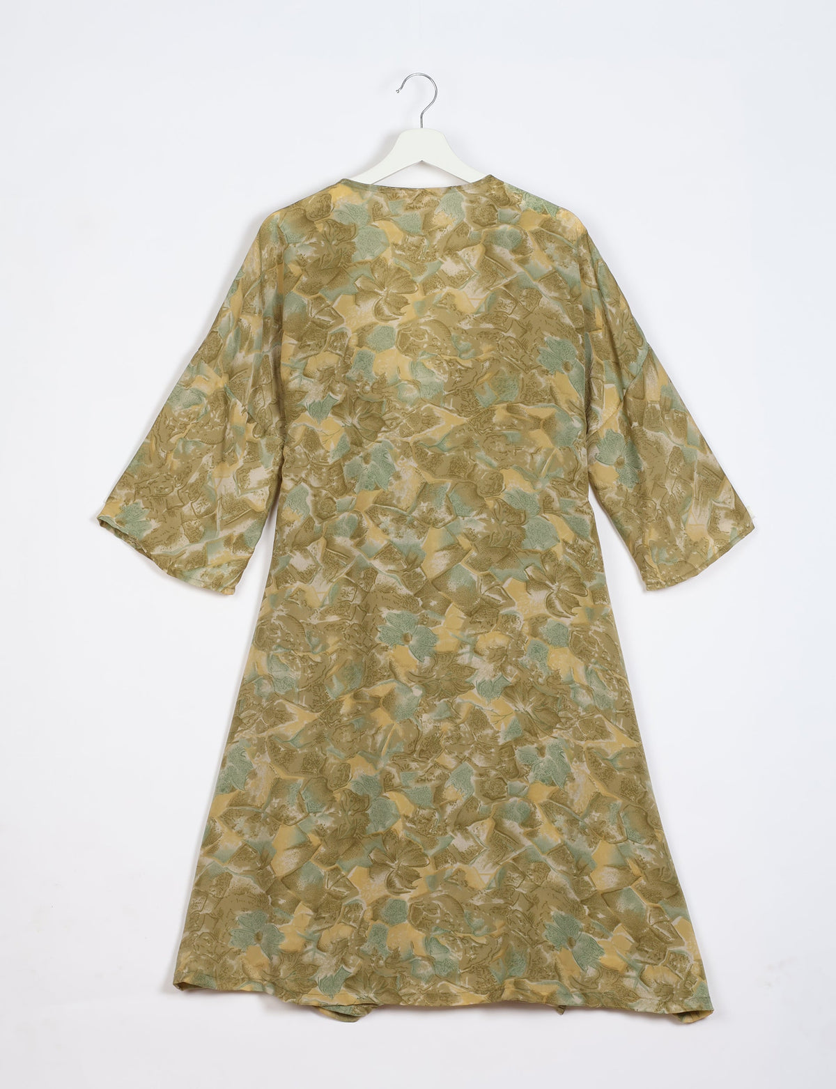 Green and beige abstract patterned coat with wide sleeves hanging on white hanger, back view