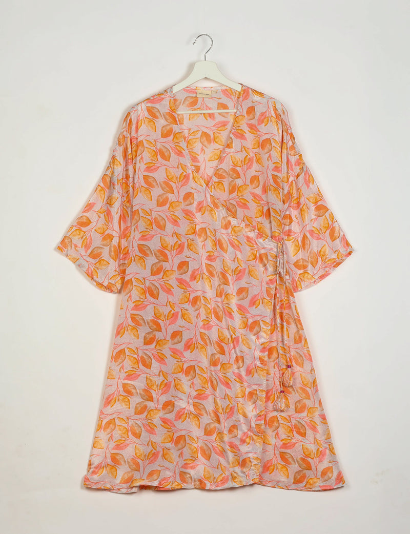 Orange and pink leaf-patterned wrap coat with three-quarter sleeves hanging on white hanger against white background