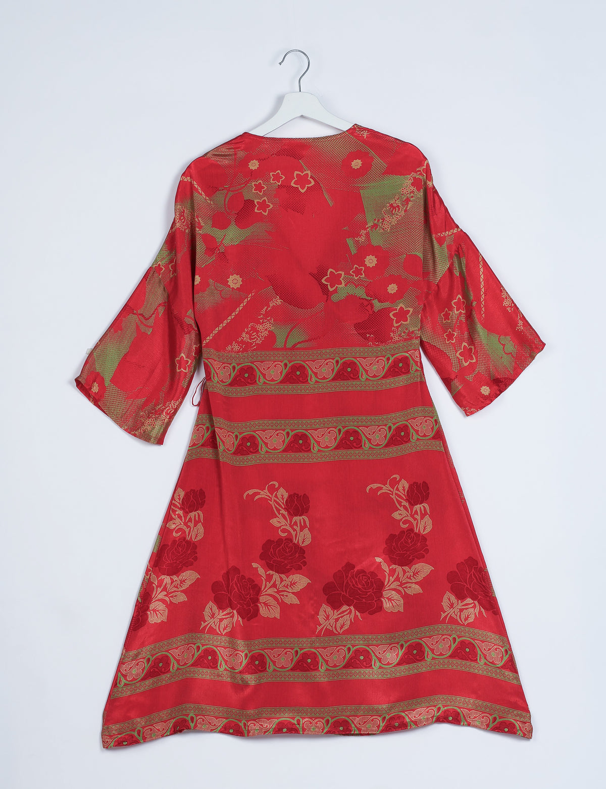 Red coat with abstract floral and geometric patterns in gold and green, shown from back on white hanger against white background