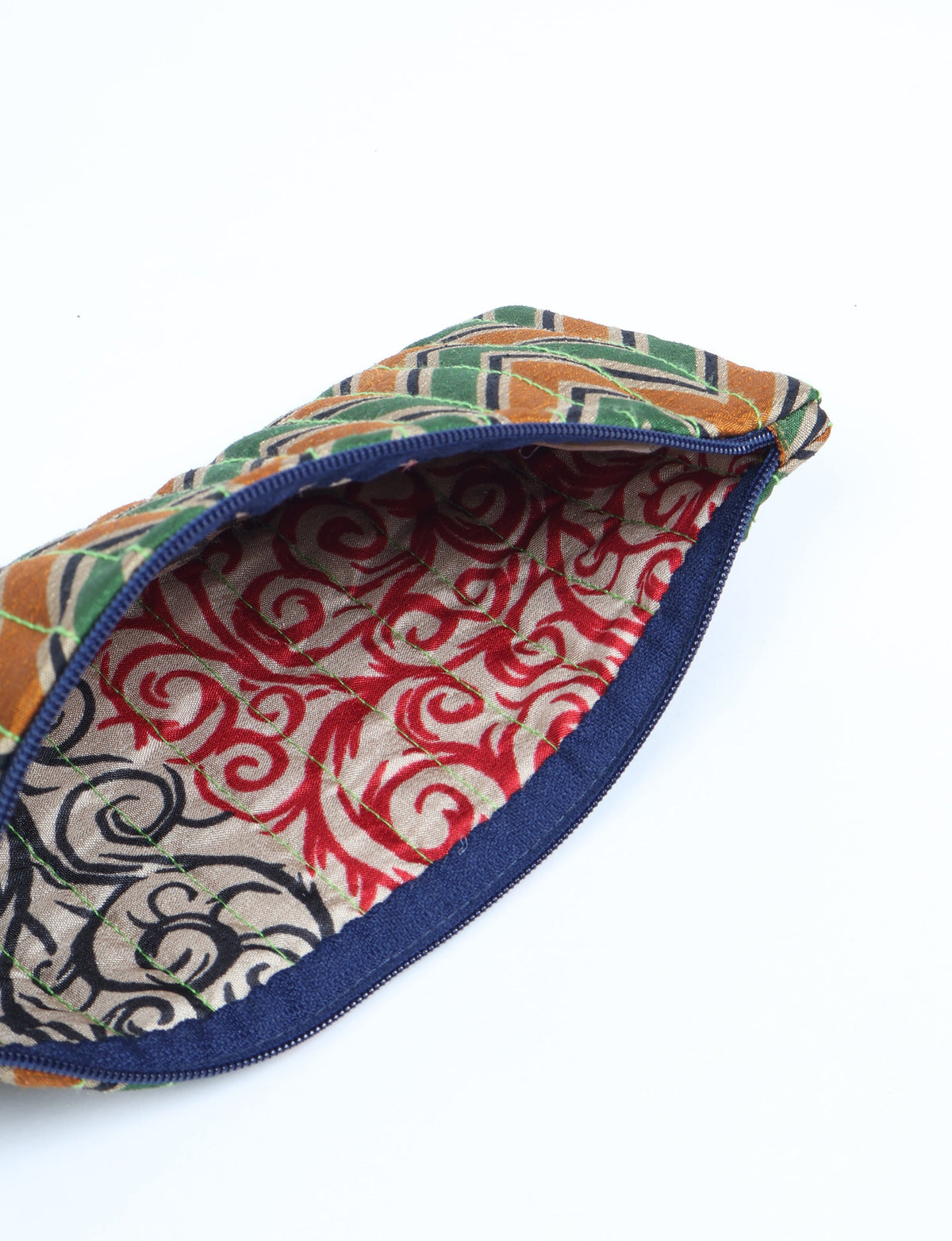 Quilted pencil pouch with blue zipper, green, orange, and black geometric exterior, and red swirl patterned interior lining