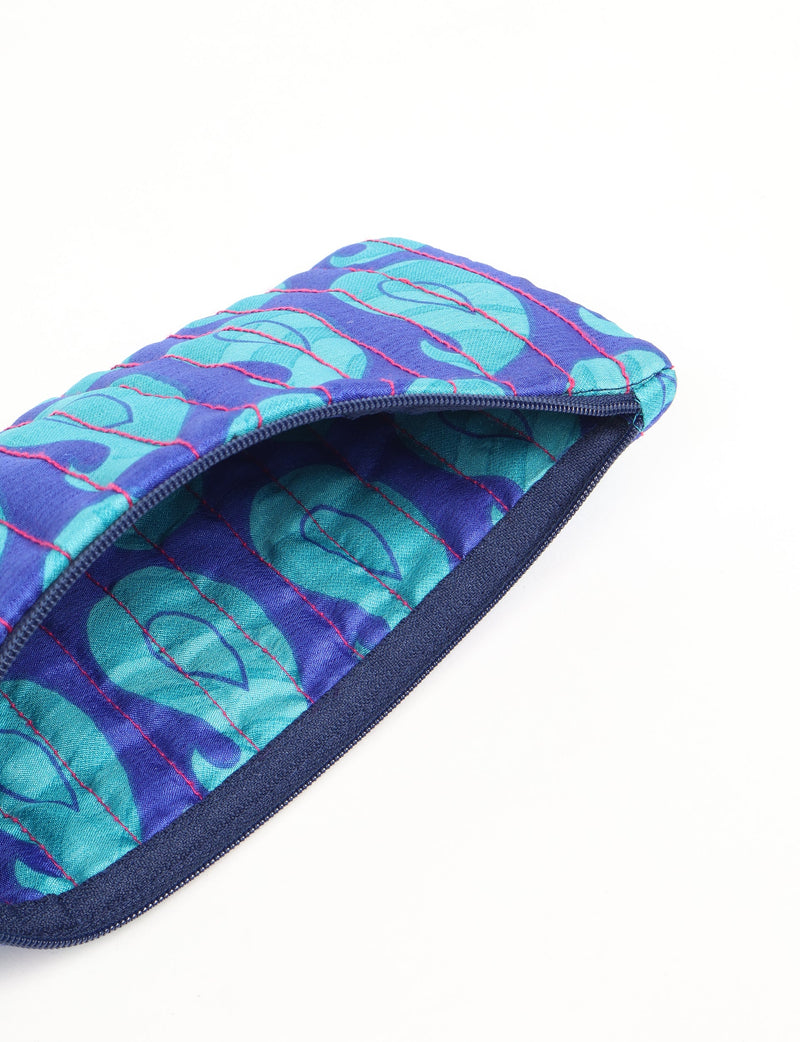 Quilted pencil pouch in blue with Indian ethnic pattern, pink stitching, and navy zipper, shown open from top angle