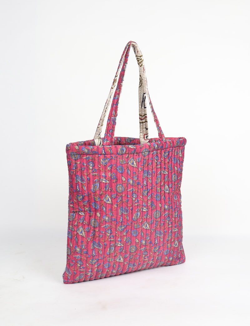 Quilted pink tropical floral shopper bag with vertical stitching and dual fabric handles, shown in side view on white background