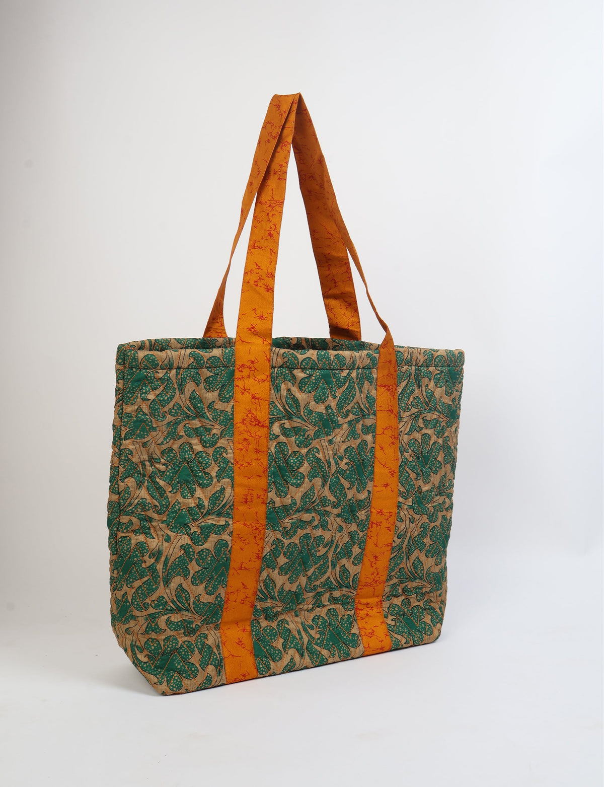 Quilted tote bag with green floral pattern on beige background and orange handles with red speckled design, front view